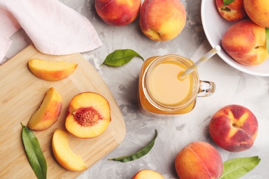 Photo of Natural peach juice and fresh fruits on grey table, flat lay