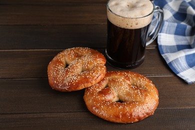 Photo of Tasty pretzels and glass of beer on wooden table