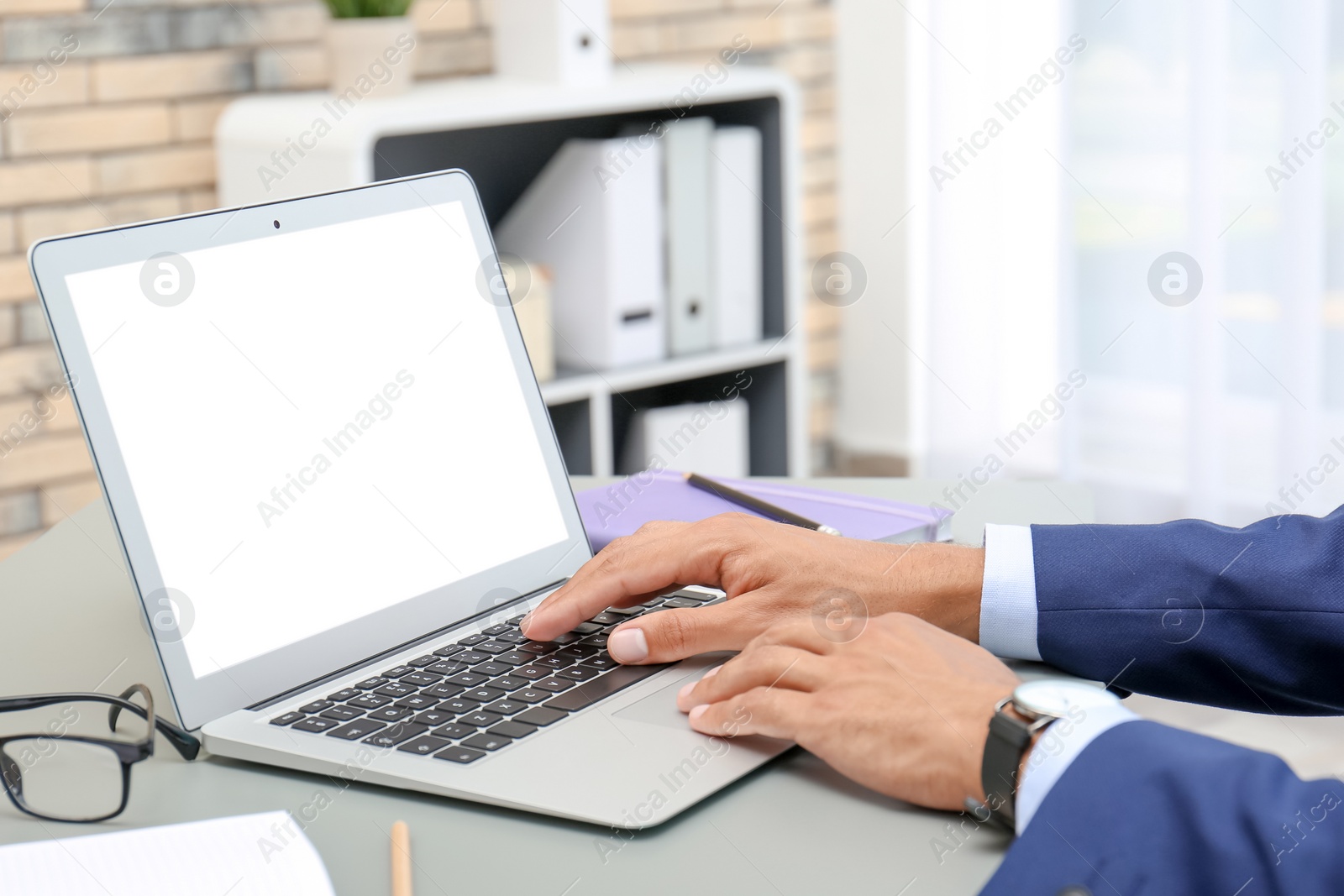 Photo of Man using laptop at table in office