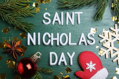 Photo of Phrase Saint Nicholas Day, gingerbread cookie and festive decor on green wooden table, flat lay