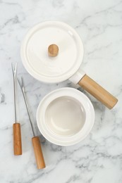 Photo of Fondue set on white marble table, flat lay