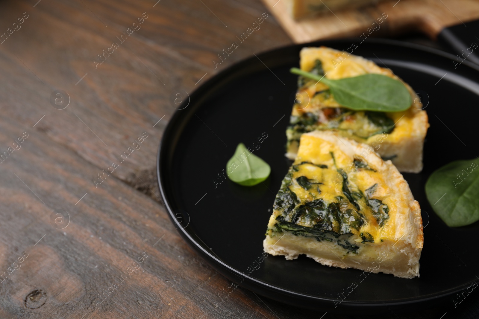 Photo of Pieces of delicious pie with spinach on wooden table, closeup. Space for text