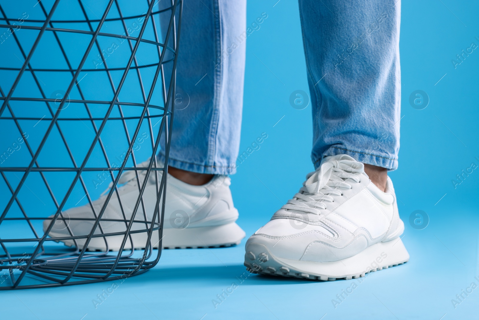 Photo of Man wearing stylish sneakers on light blue background, closeup