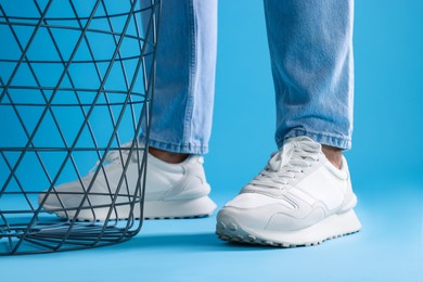 Photo of Man wearing stylish sneakers on light blue background, closeup