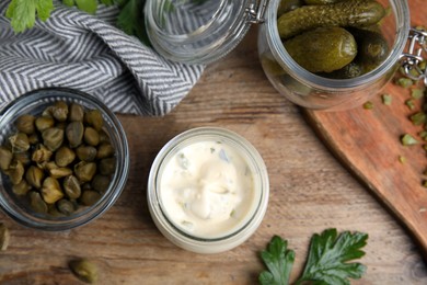 Tasty tartar sauce and ingredients on wooden table, flat lay