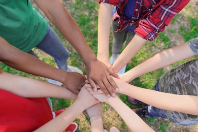 Photo of Group of children putting hands together outdoors. Summer camp