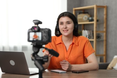 Photo of Smiling technology blogger with smartphones recording video review at home