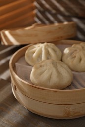 Delicious bao buns (baozi) on wooden table, closeup