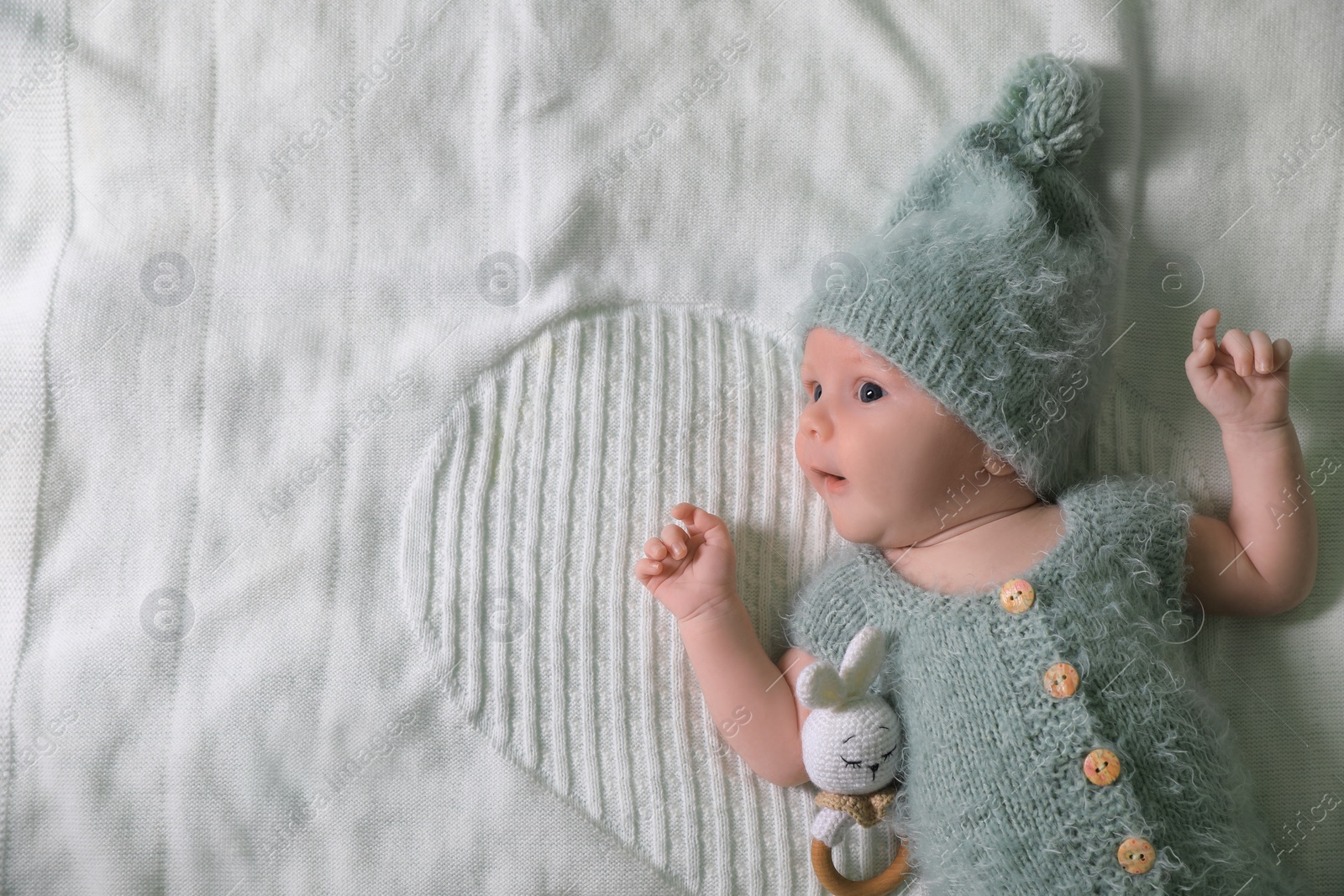 Photo of Cute newborn baby with teething toy on white blanket, top view. Space for text