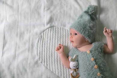 Photo of Cute newborn baby with teething toy on white blanket, top view. Space for text