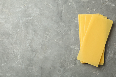 Photo of Uncooked lasagna sheets on dark marble table, top view. Space for text