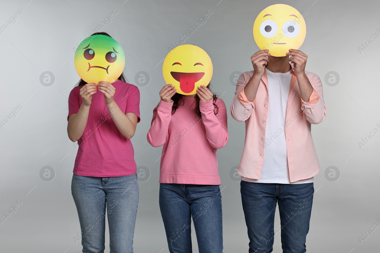 Photo of People covering faces with emoticons on grey background