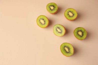 Photo of Halves of fresh kiwis on beige background, flat lay. Space for text