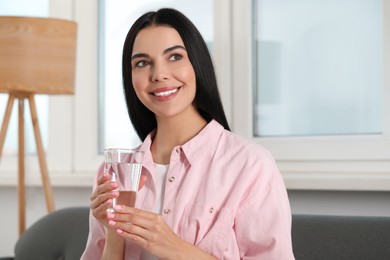 Photo of Young woman with glass of water indoors. Refreshing drink