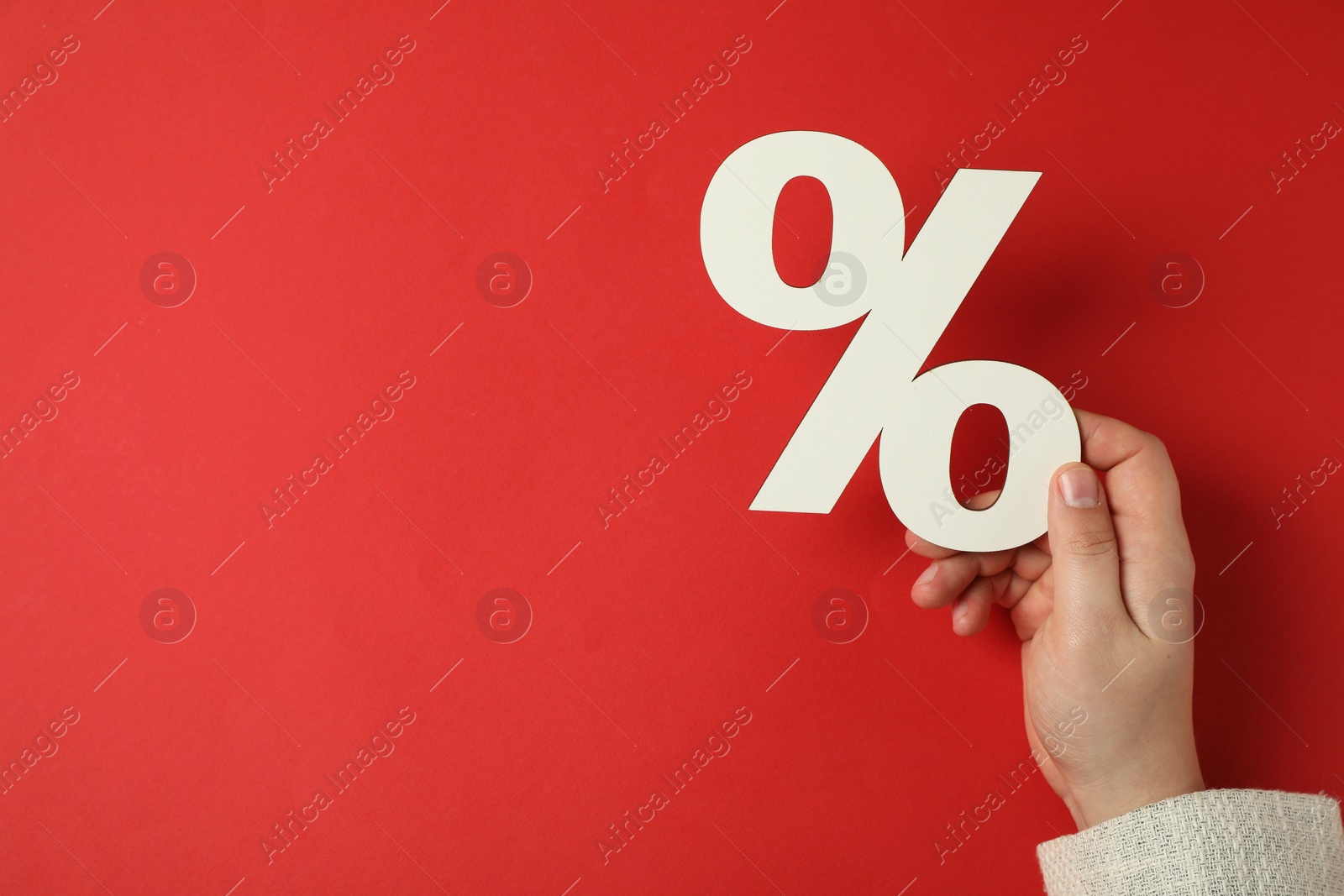 Photo of Man holding percent sign on red background, top view. Space for text