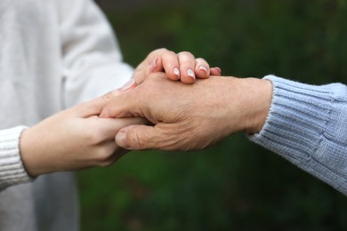 Photo of Trust and support. Woman with man joining hands outdoors, closeup