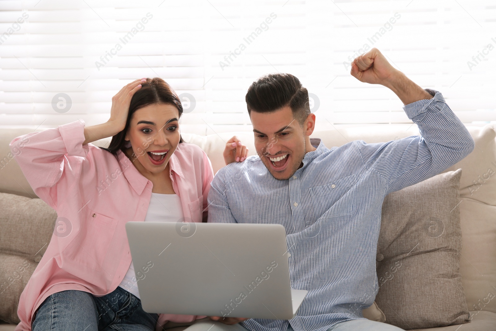 Photo of Emotional couple participating in online auction using laptop at home