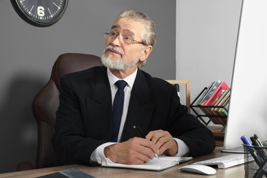 Senior boss working at wooden table in office