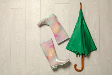 Photo of Flat lay composition with umbrella, rubber boots and space for text on wooden background