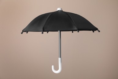 Photo of Open small black umbrella on beige background