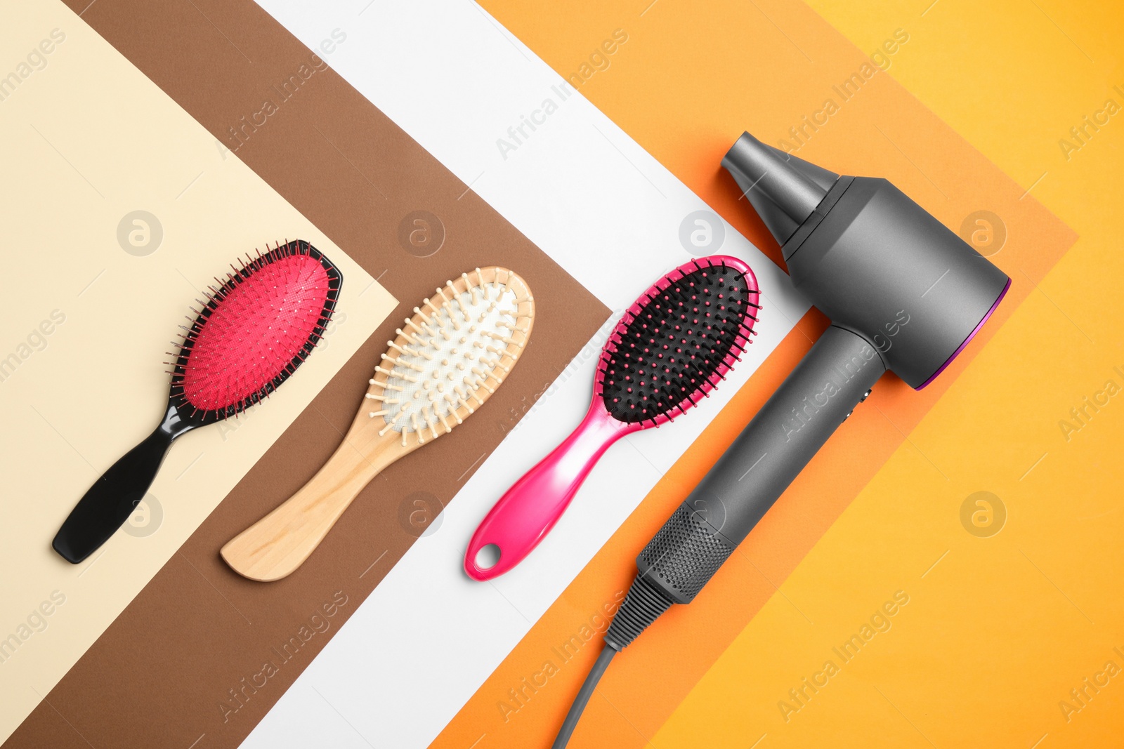 Photo of Hair dryer and different brushes on color background, flat lay. Professional hairdresser tool