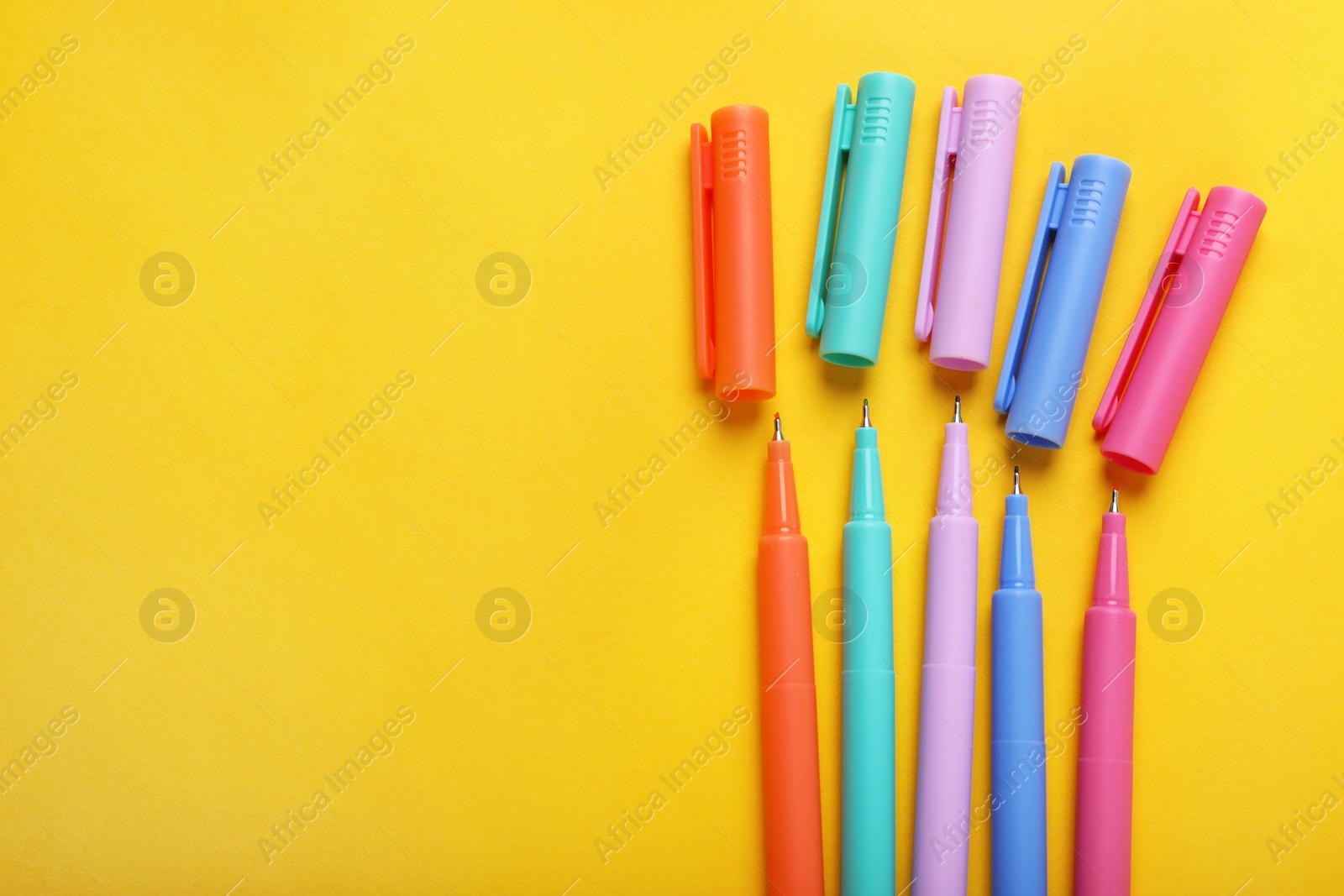 Photo of Many colorful markers on yellow background, flat lay. Space for text