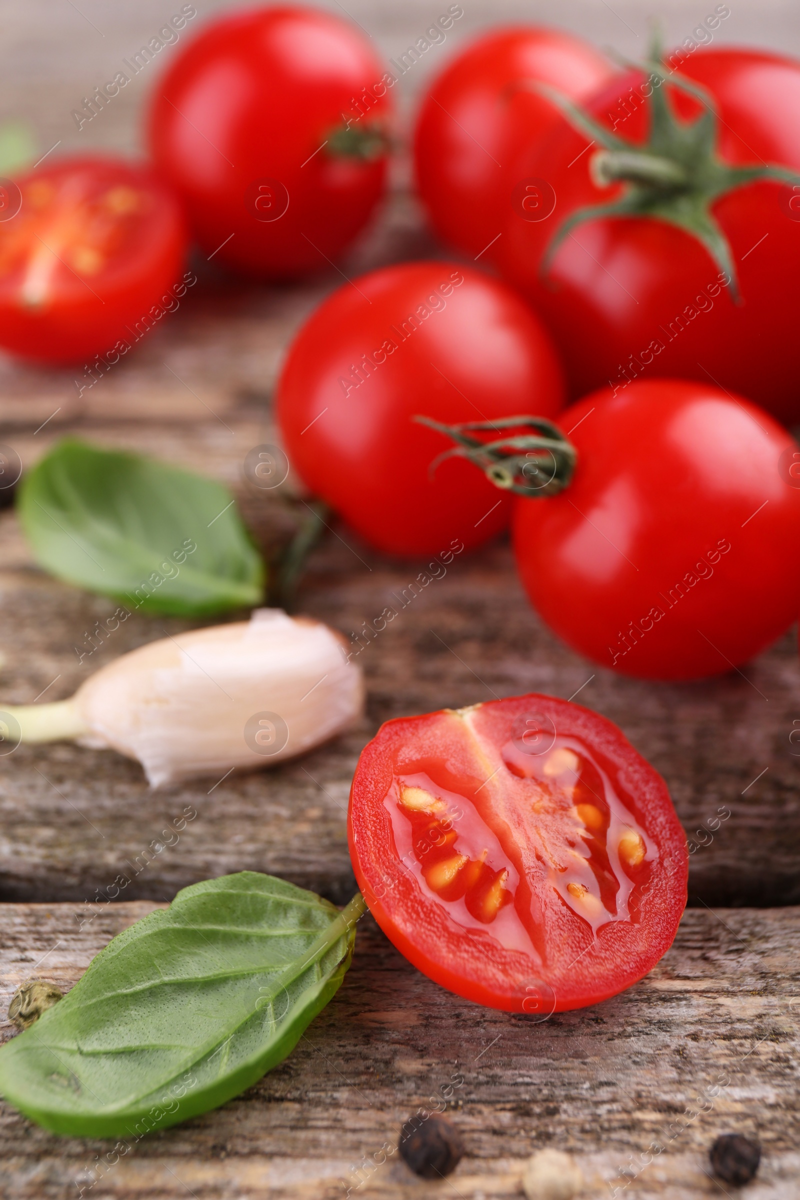 Photo of Ripe tomatoes, garlic and basil on wooden table, closeup