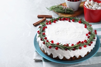 Photo of Traditional Christmas cake decorated with rosemary and cranberries on light grey marble table, space for text