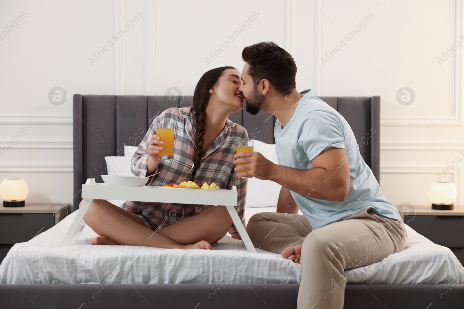 Photo of Happy couple having breakfast on bed at home