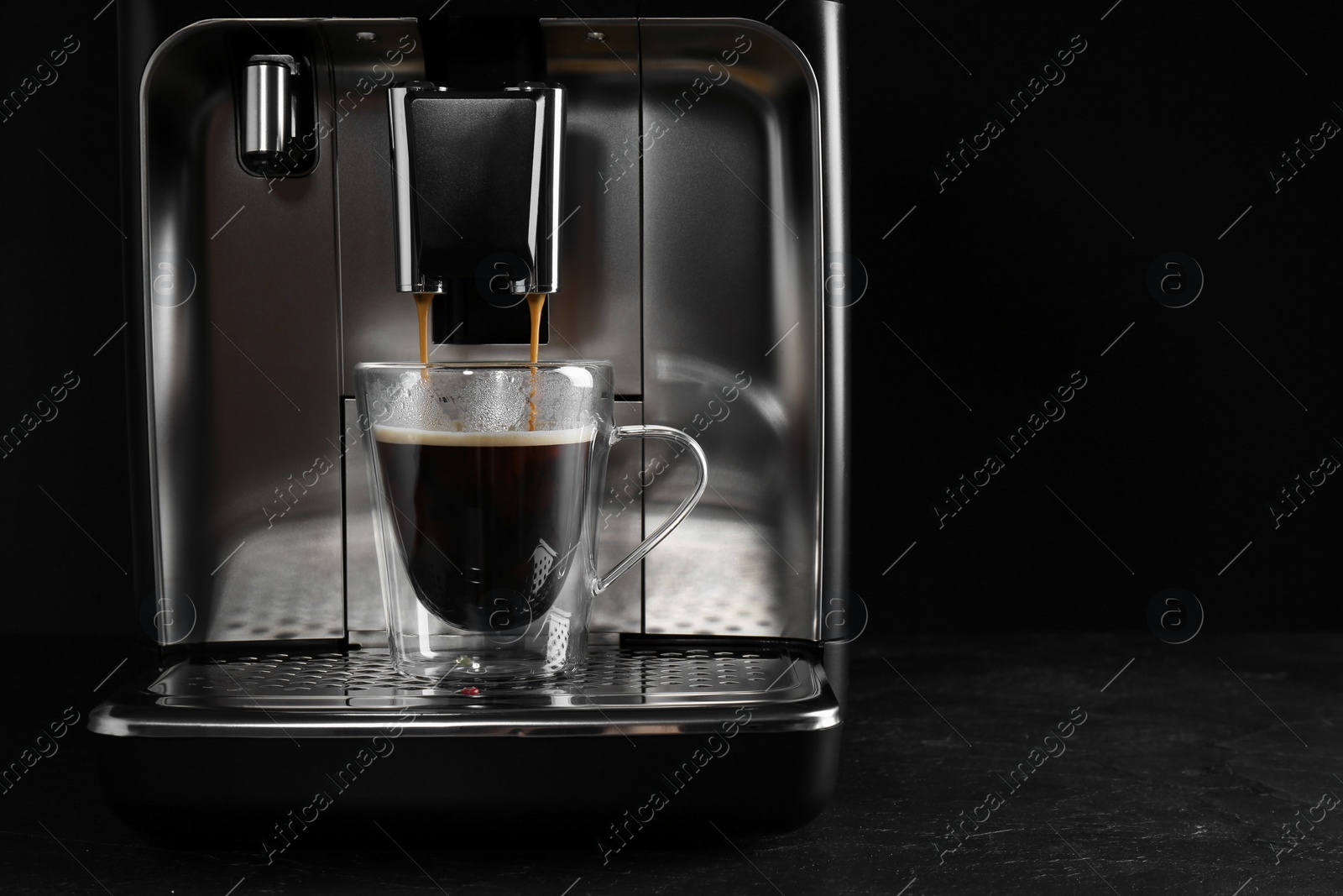 Photo of Making coffee with modern espresso machine on grey table against black background. Space for text