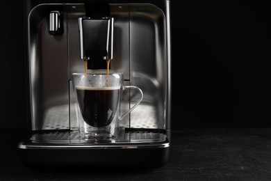 Making coffee with modern espresso machine on grey table against black background. Space for text