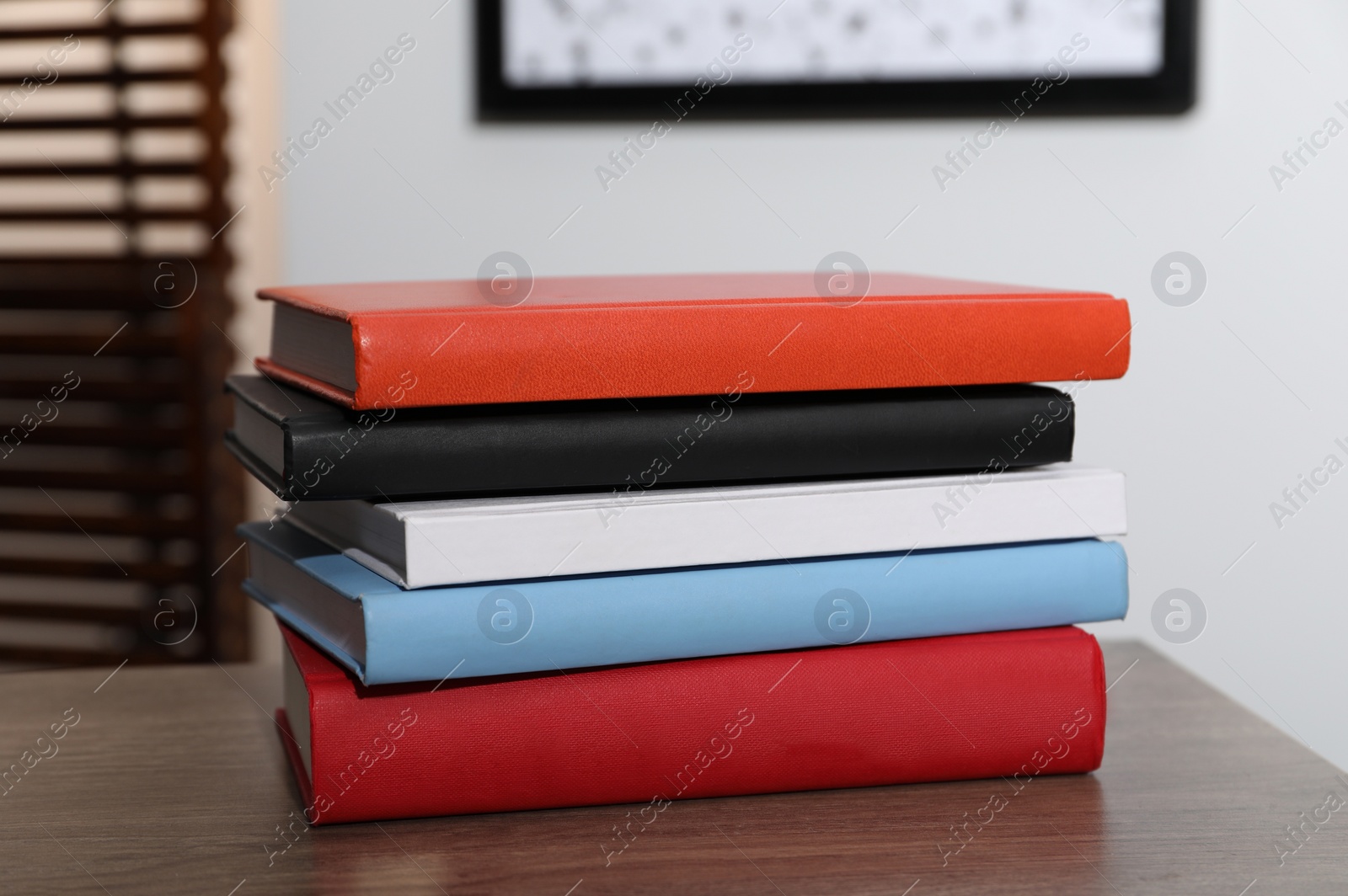 Photo of Stack of different hardcover books on wooden table indoors