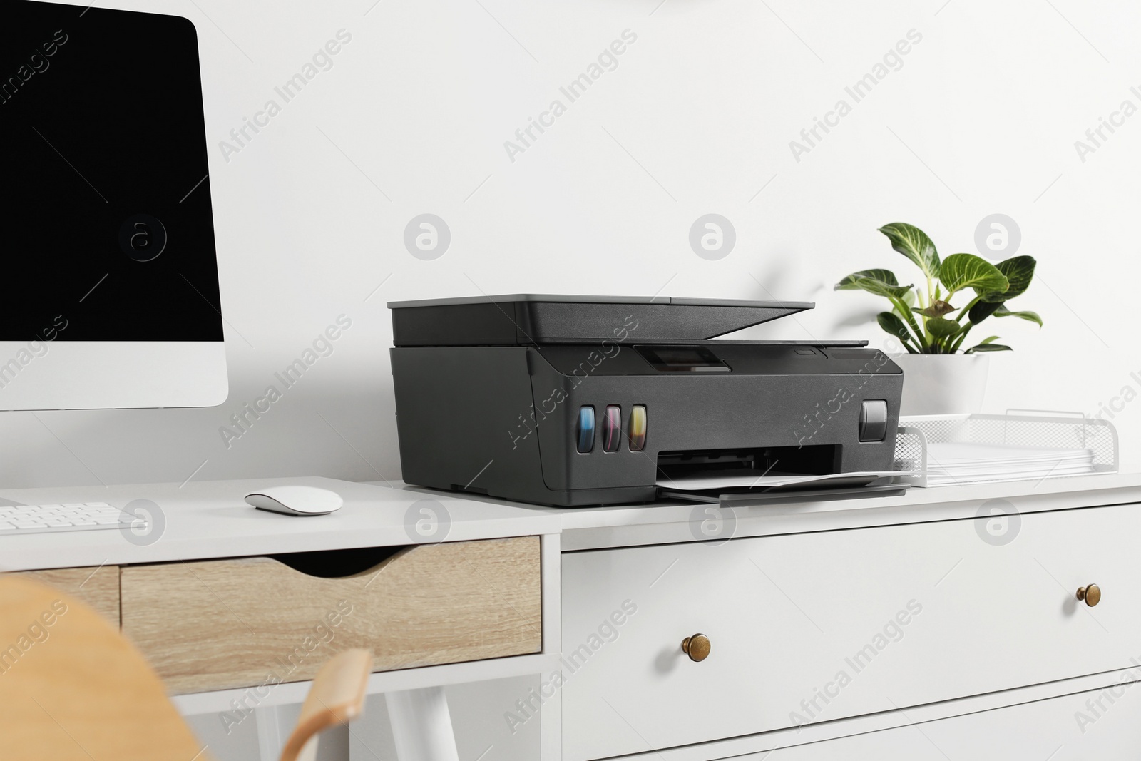 Photo of Modern printer with paper on chest of drawers indoors