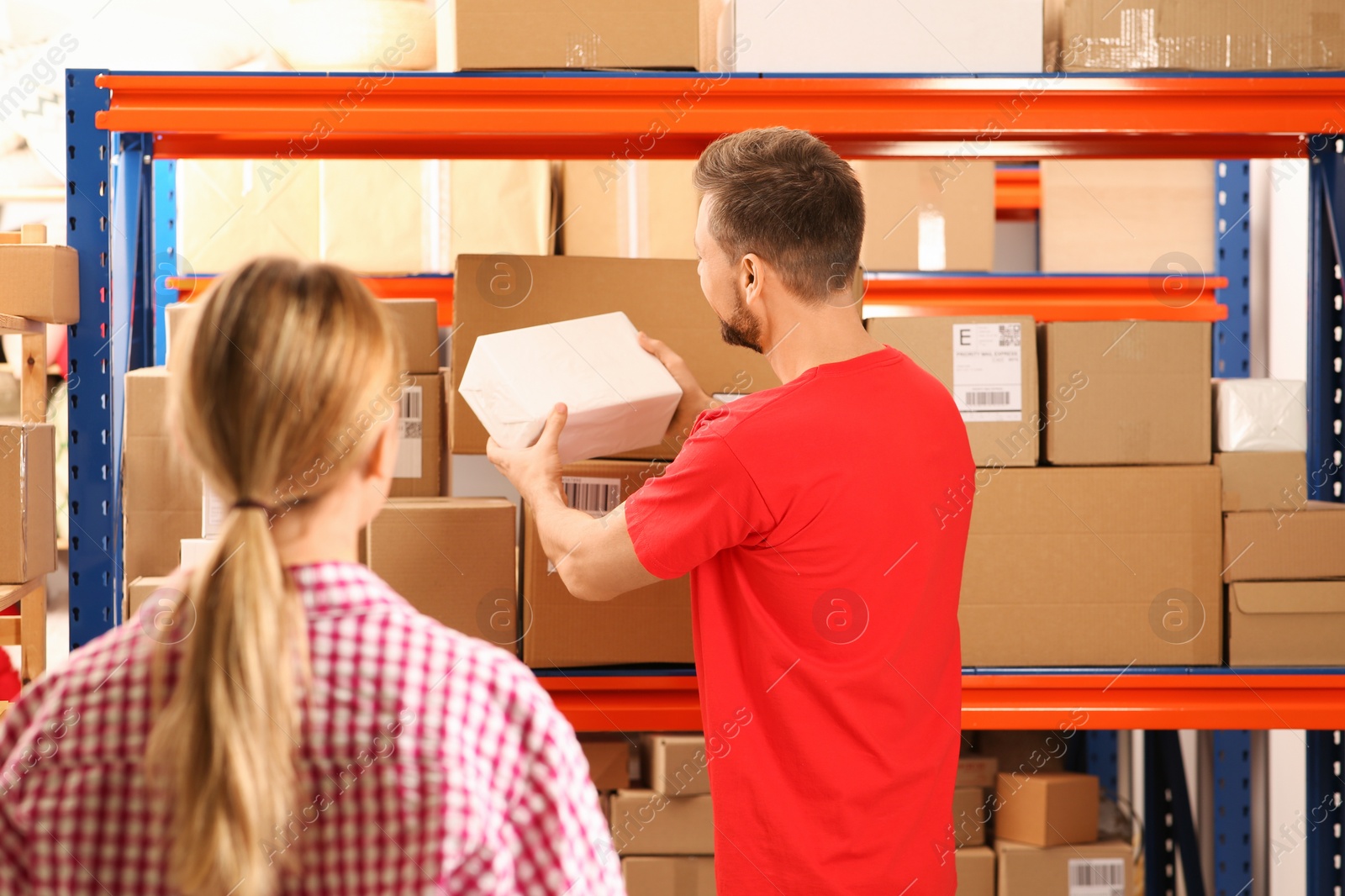 Photo of Woman and worker taking parcel from rack at post office