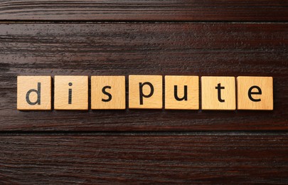 Photo of Squares with word Dispute on dark wooden table, top view