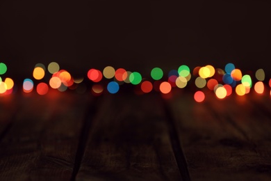 Blurred view of colorful lights on wooden table, space for text