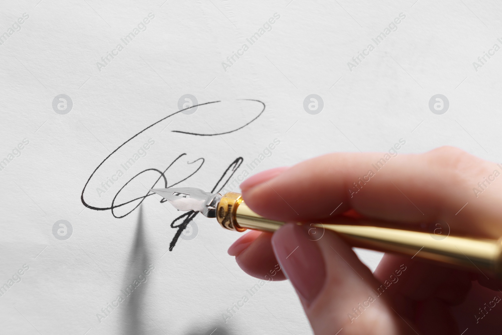 Photo of Woman signing on sheet of paper with fountain pen, closeup