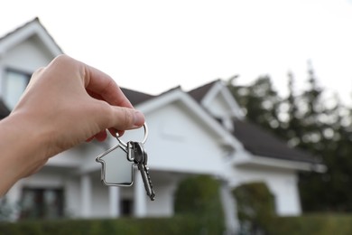 Photo of Woman holding house keys outdoors, closeup with space for text. Real estate agent