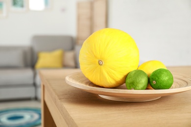 Plate of ripe fruits on wooden table in living room interior