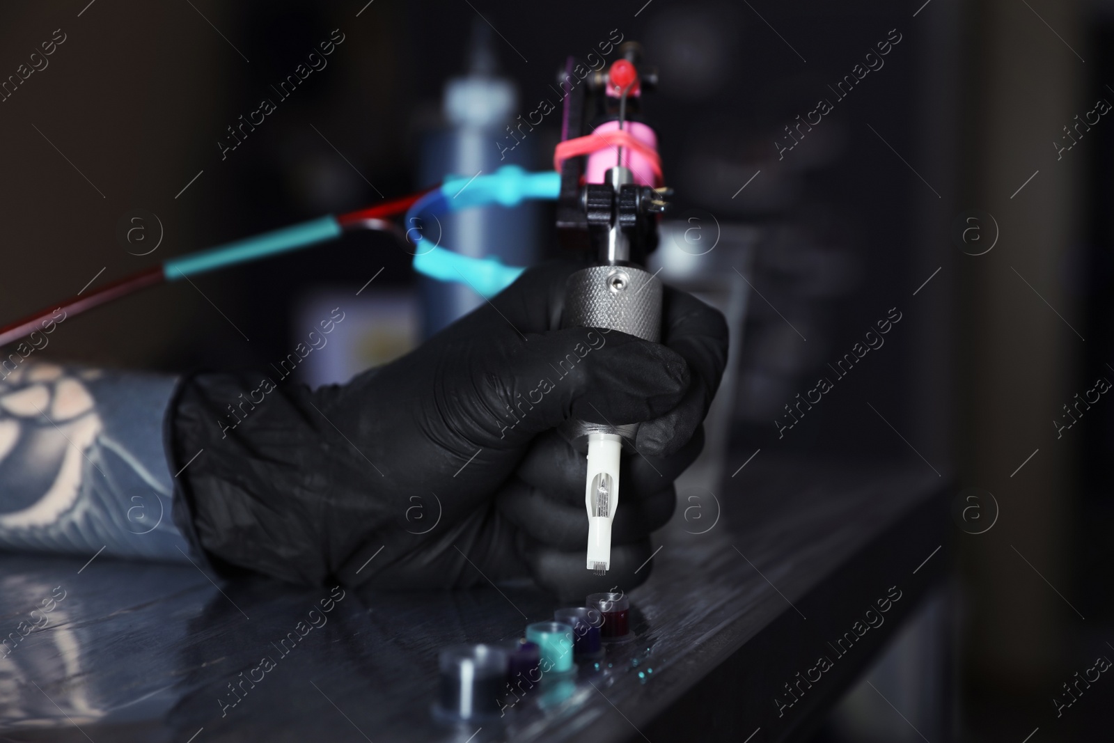 Photo of Tattoo artist with machine and ink at wooden table, closeup