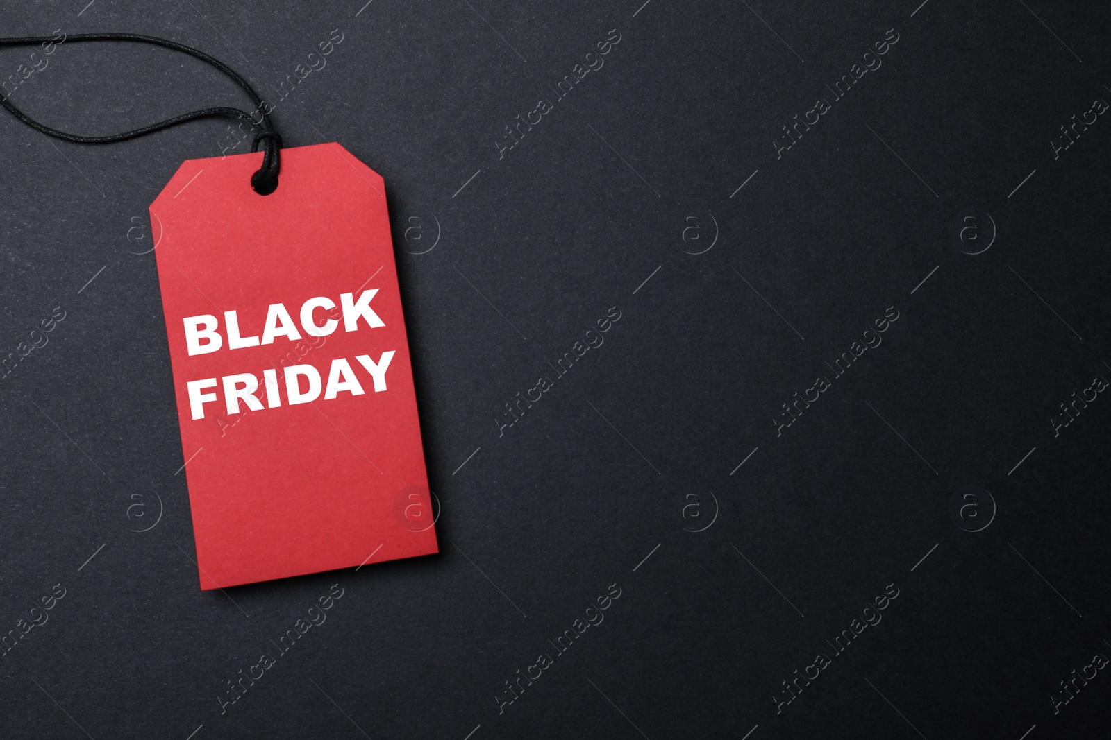 Photo of Red tag with words Black Friday on dark background, top view. Space for text