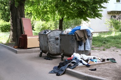 Photo of Old metal containers and scattered trash on city street