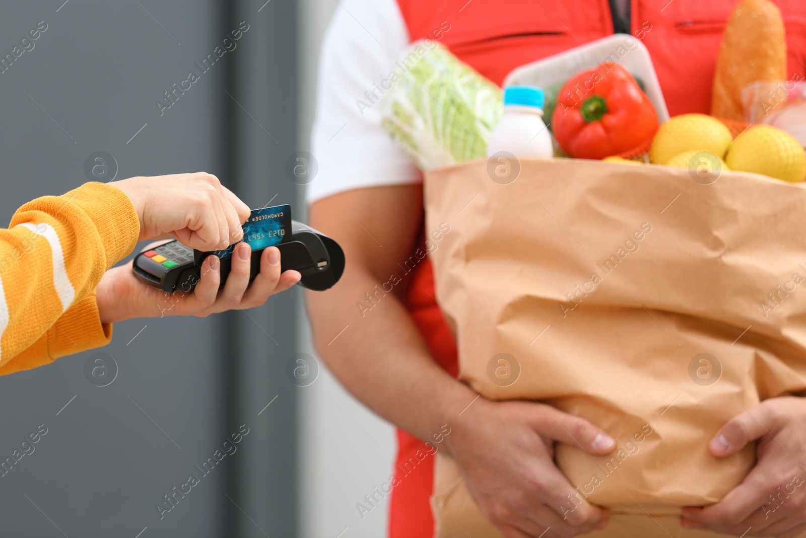 Photo of Woman using terminal to pay for food delivery indoors, closeup