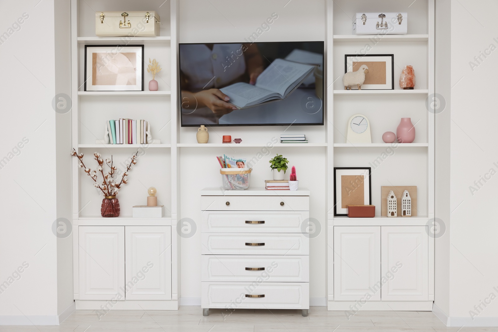 Photo of TV and shelves with different decor in room. Interior design