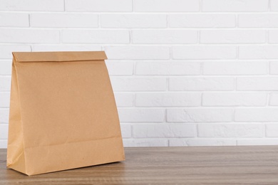 Paper bag on table against brick wall. Mockup for design