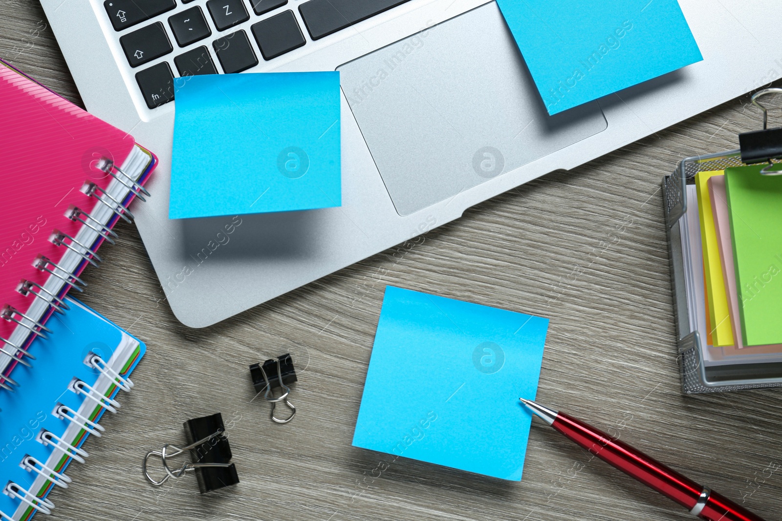 Photo of Different sticky notes, laptop and stationery on wooden table, flat lay