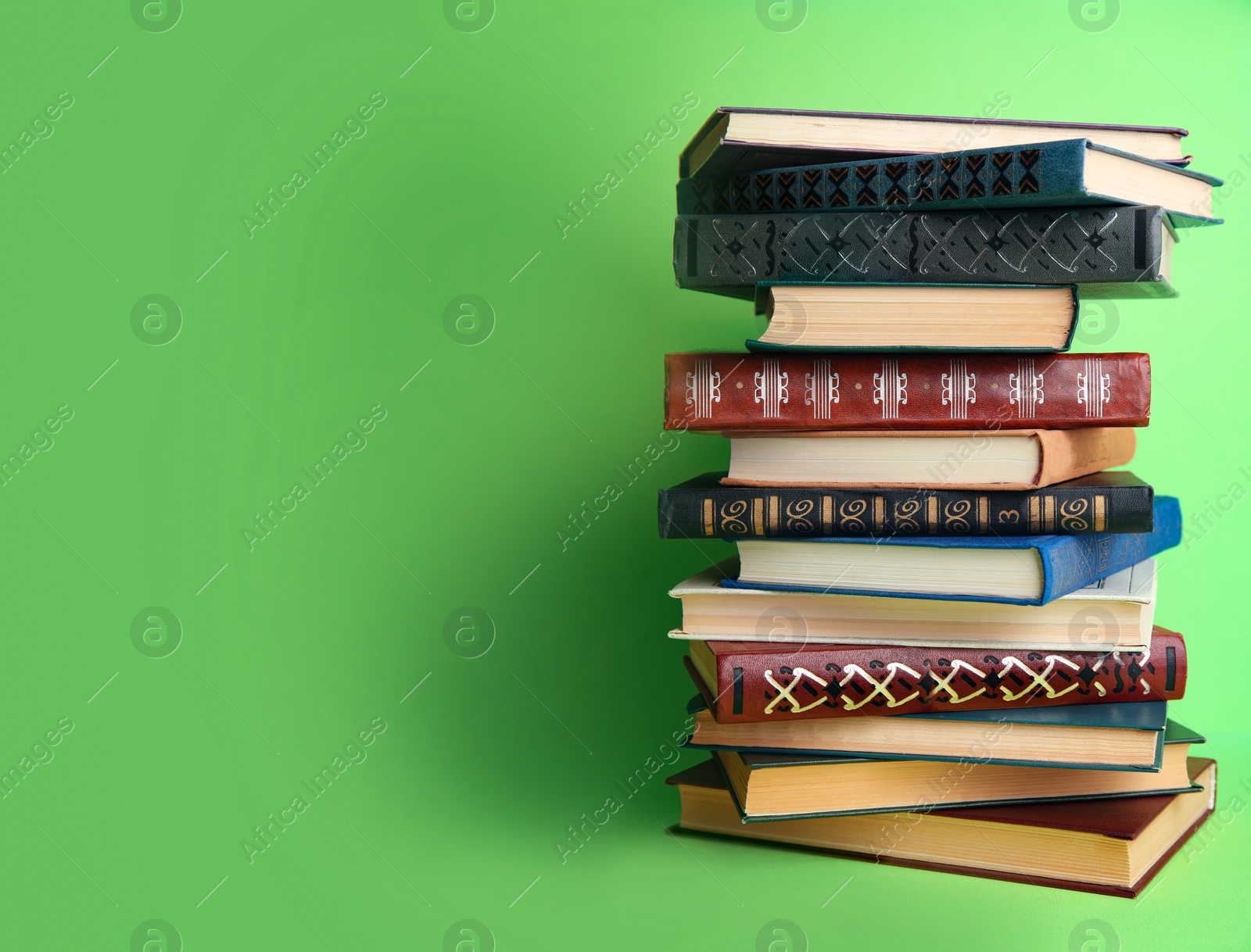 Photo of Stack of different hardcover books on green background