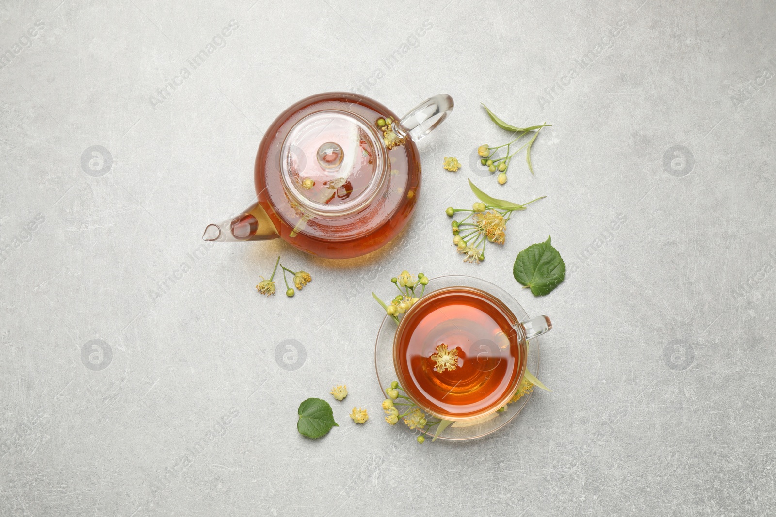 Photo of Tasty tea and linden blossom on light grey table, flat lay