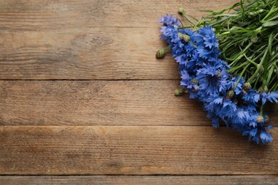 Photo of Bouquet of beautiful cornflowers on wooden table, top view. Space for text