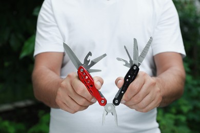 Photo of Man holding compact portable multitool outdoors, closeup